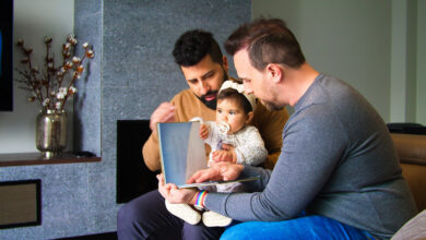 gay couple and their daughter sitting on a sofa reading a story