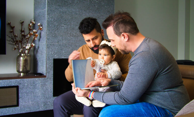 gay couple and their daughter sitting on a sofa reading a story