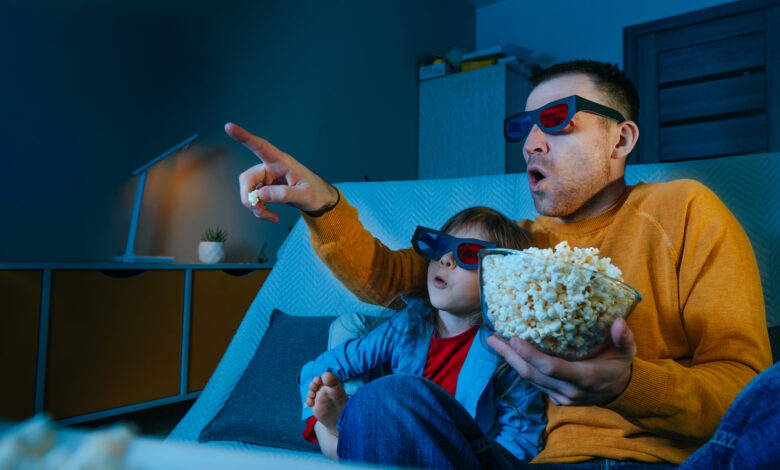 Father and daughter watching movie at home using 3D eye glasses