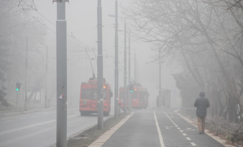 Visible air pollution at the streets of Belgrade, hazy foggy and polluted air and strong emission of CO2 due to industrial and man made pollution, with traffic moving slowly and people breathing it