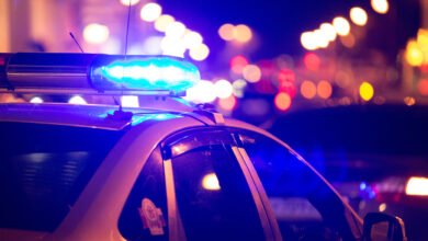 Blue light flasher atop of a police car. City lights on the back