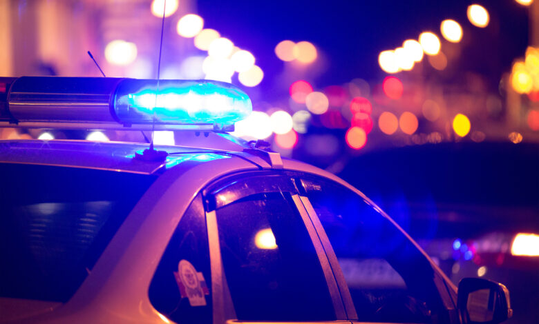 Blue light flasher atop of a police car. City lights on the back