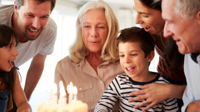 Senior white woman celebrating her birthday with family, blowing out candles on her cake, close up