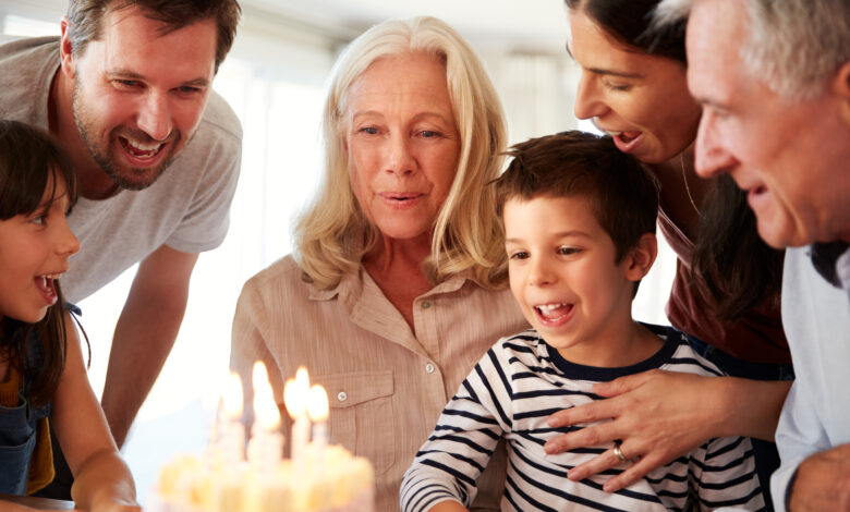 Senior white woman celebrating her birthday with family, blowing out candles on her cake, close up