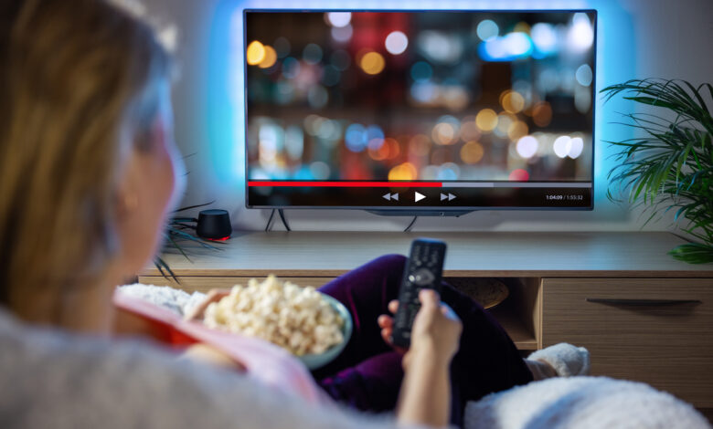 Woman relaxing at home in evening and watching TV