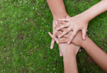 Environment conservation concept. Young children hands stack together on green nature background for sustainable development goal