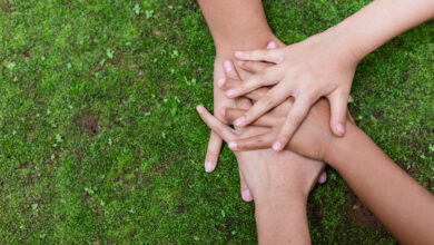 Environment conservation concept. Young children hands stack together on green nature background for sustainable development goal