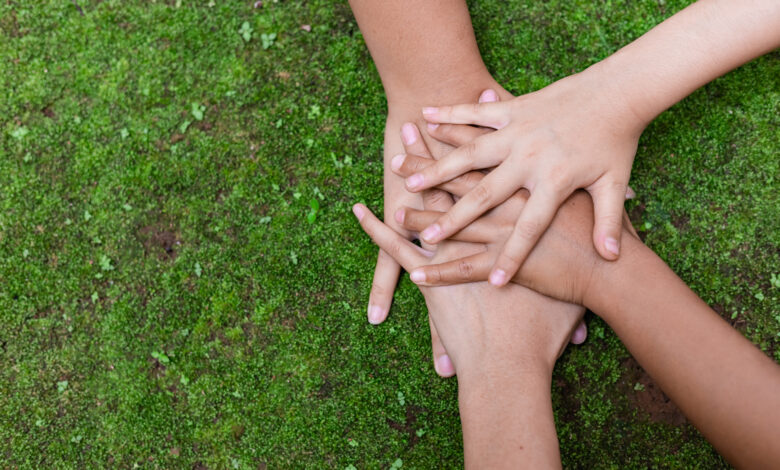 Environment conservation concept. Young children hands stack together on green nature background for sustainable development goal