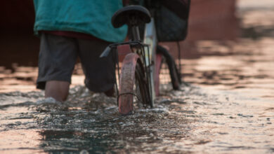 Biker on a flooded road during a flood caused by heavy rain, Tha