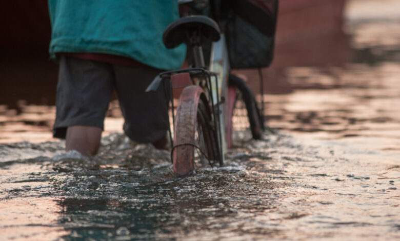 Biker on a flooded road during a flood caused by heavy rain, Tha